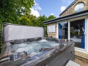 Een bubbelbad met gebruiksaanwijzing, omgeven door een stenen gebouw en weelderige begroeiing.