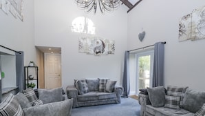 A spacious living room with grey sofas and matching cushions, a large window with a view, and decorative wall art.