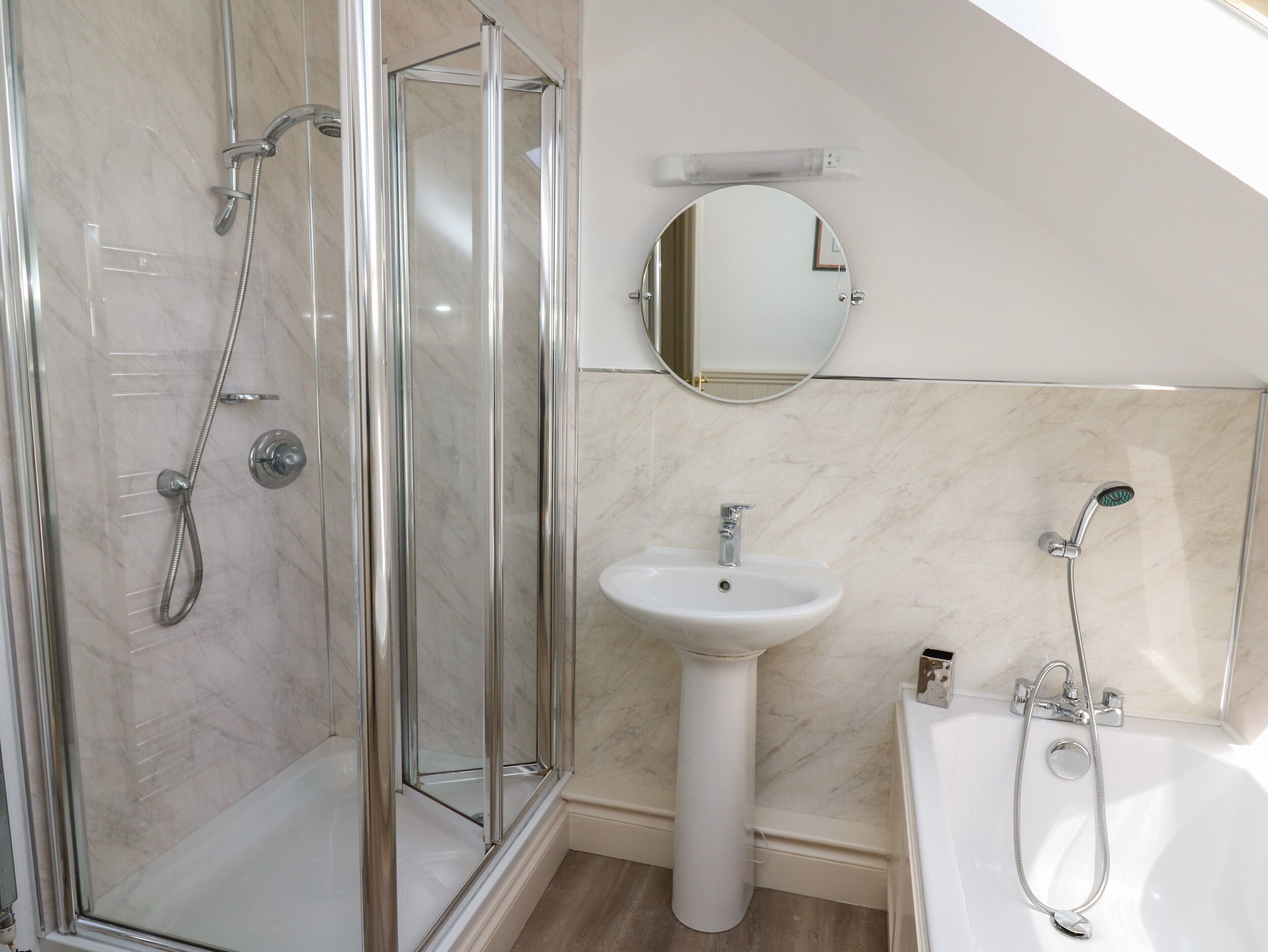 A modern bathroom with a glass-enclosed shower, a pedestal sink, and a bathtub.