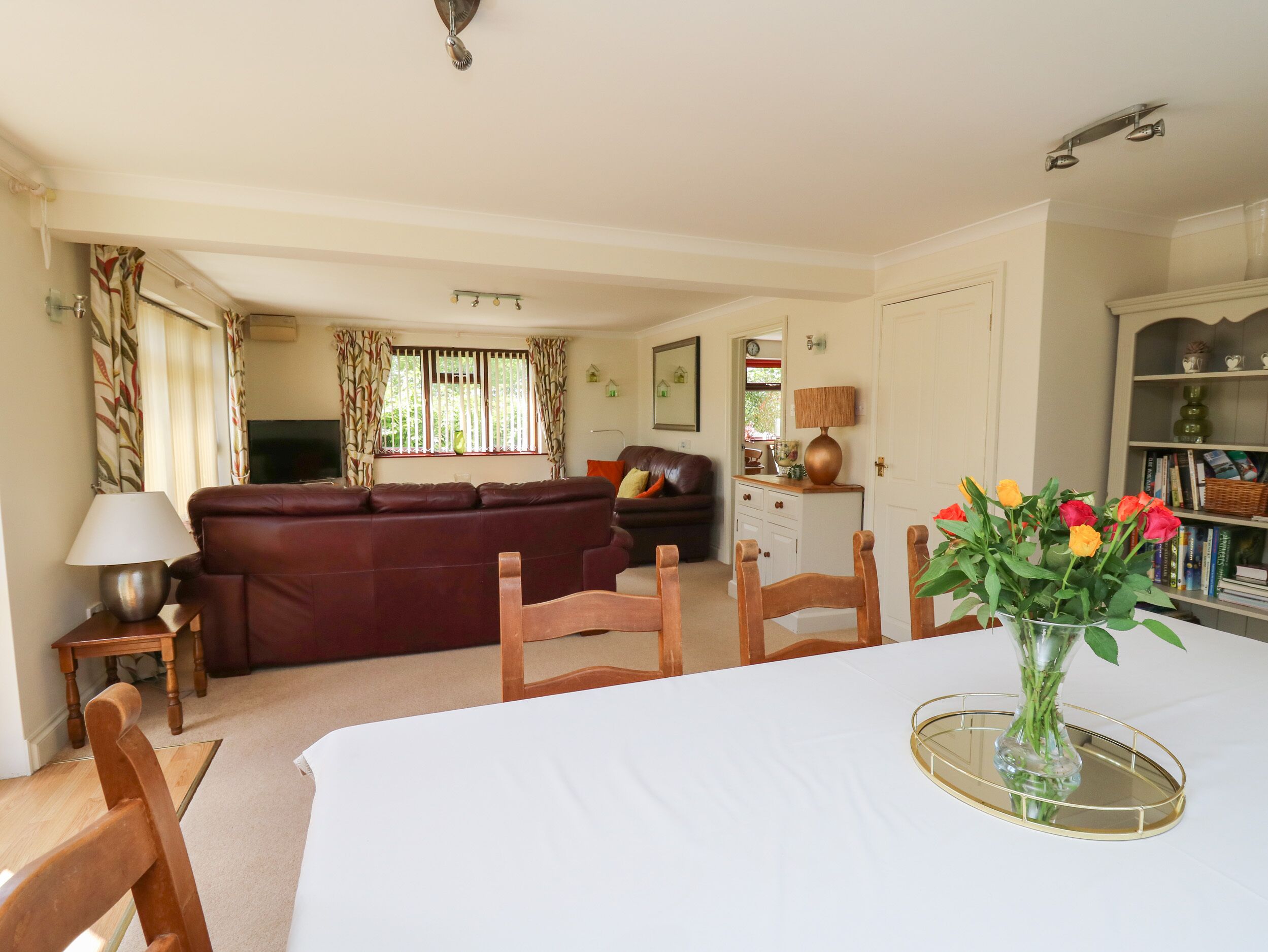 A living room with a sofa, chairs, a dining table, and a TV.