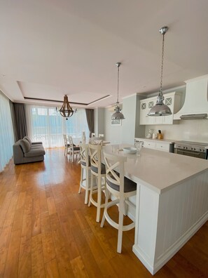 A modern kitchen with a central island, white cabinetry, and a dining area with chairs and a sofa. - Large Luxury Enclosed Villa, Perfect Location (Tibubeneng)