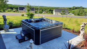 Ein Whirlpool auf einer Terrasse mit Blick auf eine Wohngegend und Hügel.