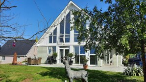 Ein zweistöckiges Haus mit großem Vorgarten, einer Hirschstatue und einer Garage.