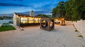Ett modernt hus med ett stort rum med stora fönster, en grusbelagd innergård och en unik, cirkelformad sittgrupp.