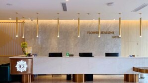 A hotel reception desk with a modern design, featuring a marble countertop, a reception area with a wooden panel backdrop, and a sign that reads "Flower Seasons Hotel". - Flower Seasons Hotel (Dafang)