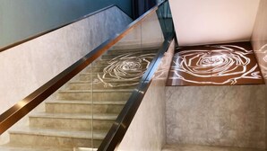 A staircase with a glass railing and a rose pattern on the steps. - Flower Seasons Hotel (Dafang)