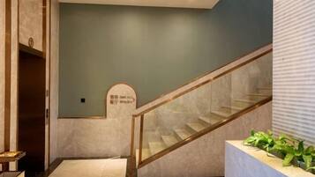 A staircase with glass railings leading to a landing with a sign.