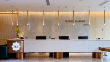A hotel reception desk with a modern design, featuring a marble countertop, a reception area, and a wall-mounted sign.