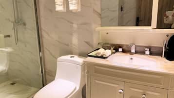 Een moderne badkamer met een douchecabine van glas, een wit toilet en een beige wastafel met een wastafel en spiegel.