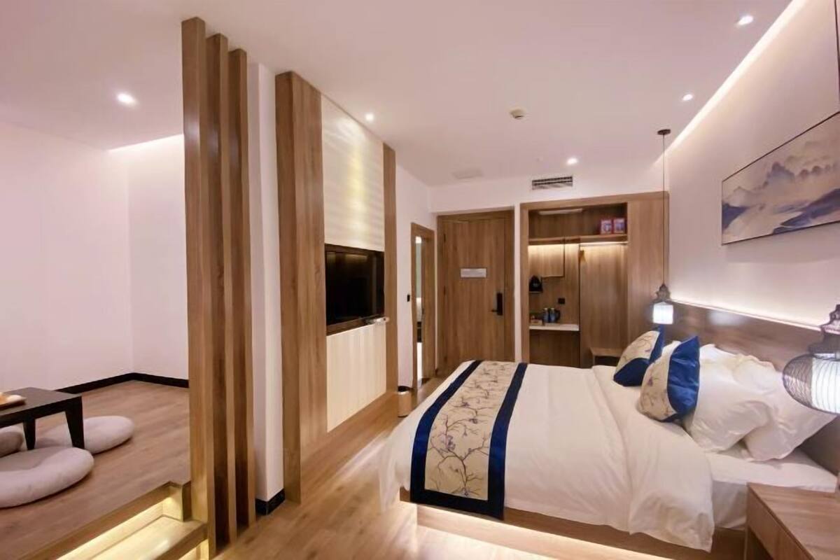 A modern hotel room with a large bed, wooden wardrobe, and a TV.