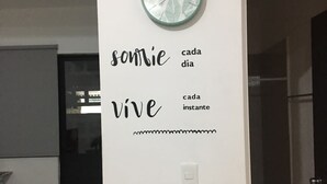 A wall with a clock and inspirational text in a room with a door and a tiled floor.