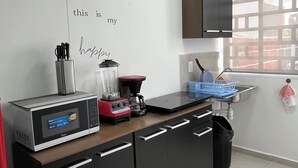 A modern kitchen with a microwave, coffee maker, and a sink.