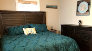 A bedroom with a bed, wooden headboard, a nightstand, a dresser, and a wall decoration. - Pool spacious home in the heart of town (St. Petersburg)