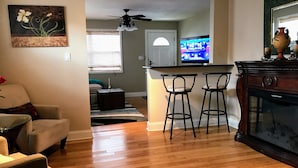 A living room with a wooden floor, a sofa, a coffee table, and a TV in the background. - Pool spacious home in the heart of town (St. Petersburg)