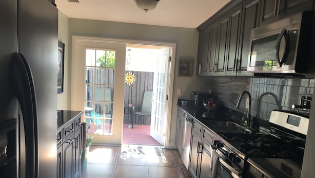 A kitchen with stainless steel appliances, a tiled floor, and a view to an outdoor patio area. - Pool spacious home in the heart of town (St. Petersburg)