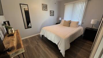 A bedroom with a bed, bedside tables, a mirror, and a ceiling fan.