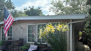 Ein Holzhaus mit Veranda, Gartenmöbeln und einer großen amerikanischen Flagge.