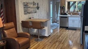 Eine geräumige Küche mit Holzboden, einer Bar und einem Esszimmerstuhl.