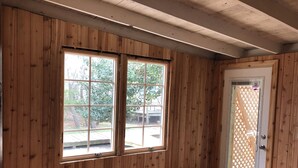 Ein Zimmer mit Holzwandverkleidung, einer Tür mit Gittermuster und einem Lüftungsgitter am Boden.