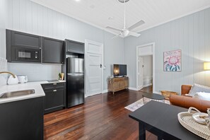 Cozy living space with a comfortable couch, round table, and modern kitchen appliances.