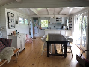 A spacious kitchen with a dining table and chairs, wooden floors, and white cabinetry.
