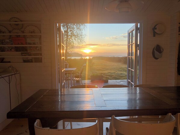 An open dining area with a view of the sunset over a grassy landscape.