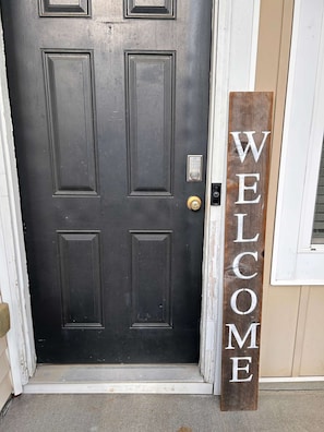A black door with a keypad lock and a wooden welcome sign. - Cozy little Townhouse 7 minutes from Carowinds (Charlotte)