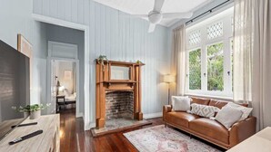 Une pièce avec une cheminée, un canapé en cuir, une table basse en bois et une grande fenêtre avec des rideaux.