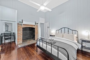 Classic bedroom with a large bed, brick fireplace, and a desk for work.