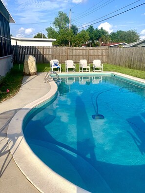 A swimming pool with a wooden deck, a covered object, and a row of chairs. - POOL,3 BR Merritt Island, Cocoa Bch, Port Canaveral, USSSA fields,KSC (Merritt Island)