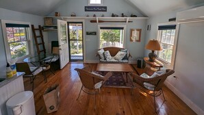 A cozy room with a loft bed, a dining table, wicker chairs, and a ceiling fan.