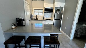A modern kitchen with a central island, bar stools, and built-in appliances. - Brand New Beach Condo 2BD 1BA w/Parking (Point Pleasant Beach)