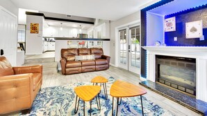 Ein modernes Wohnzimmer mit Kamin, Ledersofa und Essbereich.