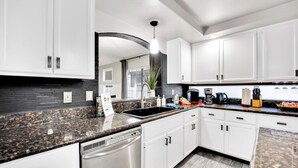 Eine moderne Küche mit weißen Schränken, Granit Arbeitsplatten und einem Geschirrspüler.