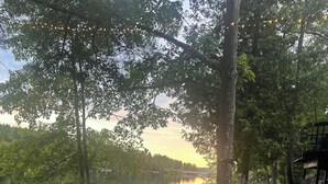 Une terrasse au bord du lac avec un hamac, une jetée avec des chaises et une structure en bois.