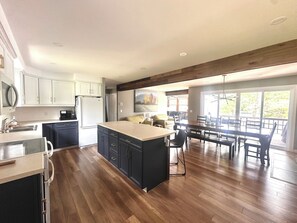 Une cuisine moderne dotée d’un grand îlot central, d’un plancher en bois et d’un coin repas avec une table et des chaises.