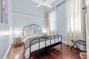 Classic bedroom with a single bed, bedside table, and lamp, set against a light blue backdrop.