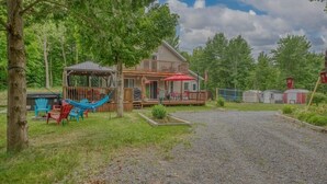 A cabin with a porch, a hammock, and a red umbrella.
