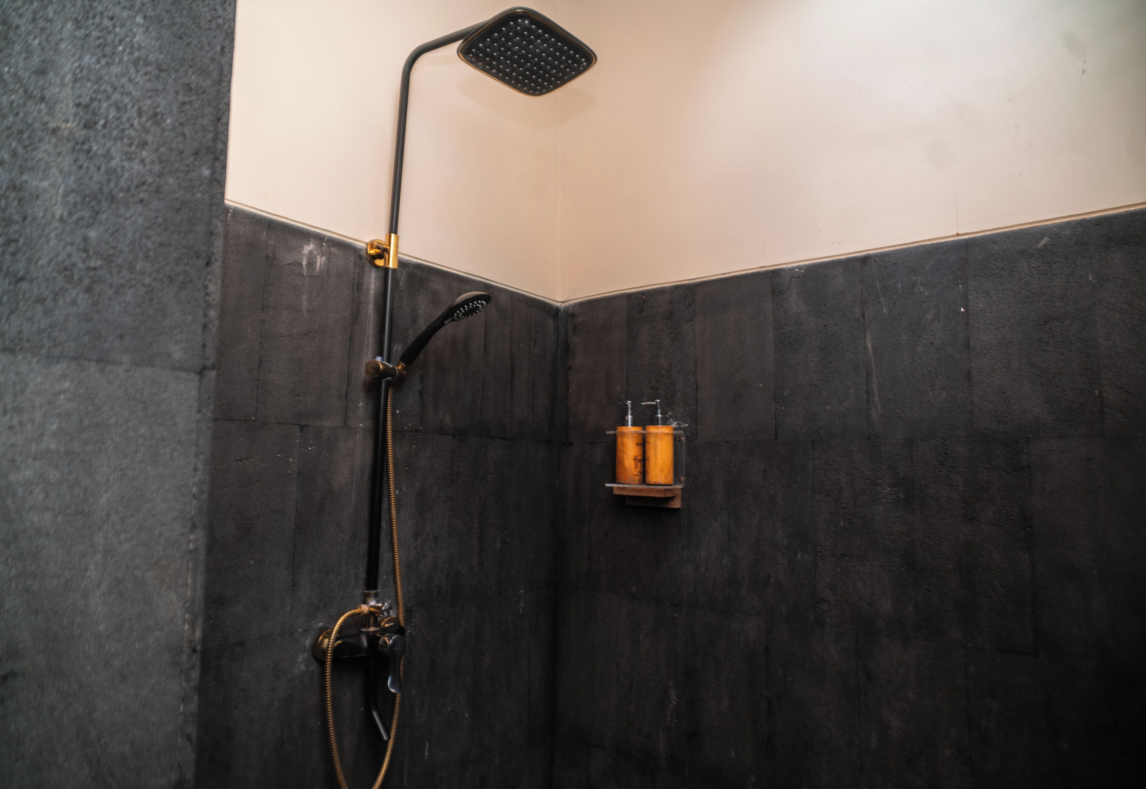 A shower with a handheld showerhead and a wall-mounted faucet.