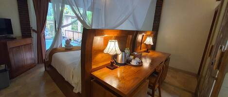 Une chambre à coucher avec un lit en bois, une table de chevet avec des lampes, une télévision et une vue sur l’extérieur.