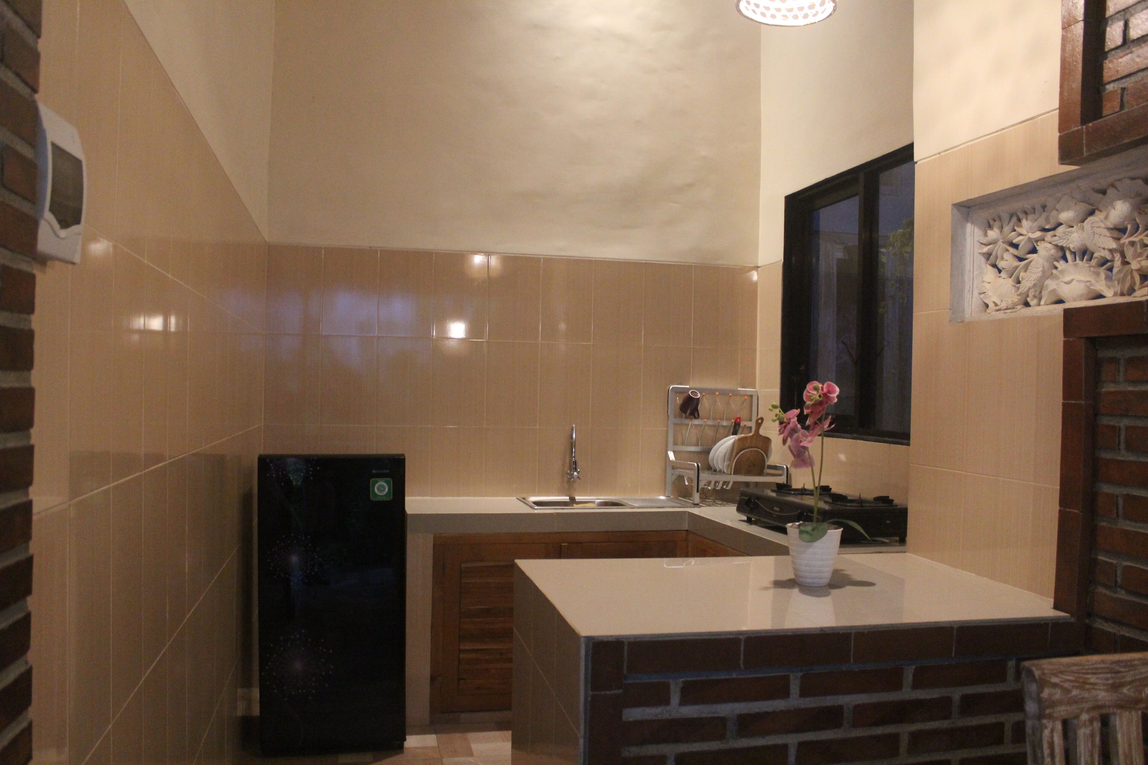 A compact kitchen with a built-in refrigerator, a sink, and a window above the counter.