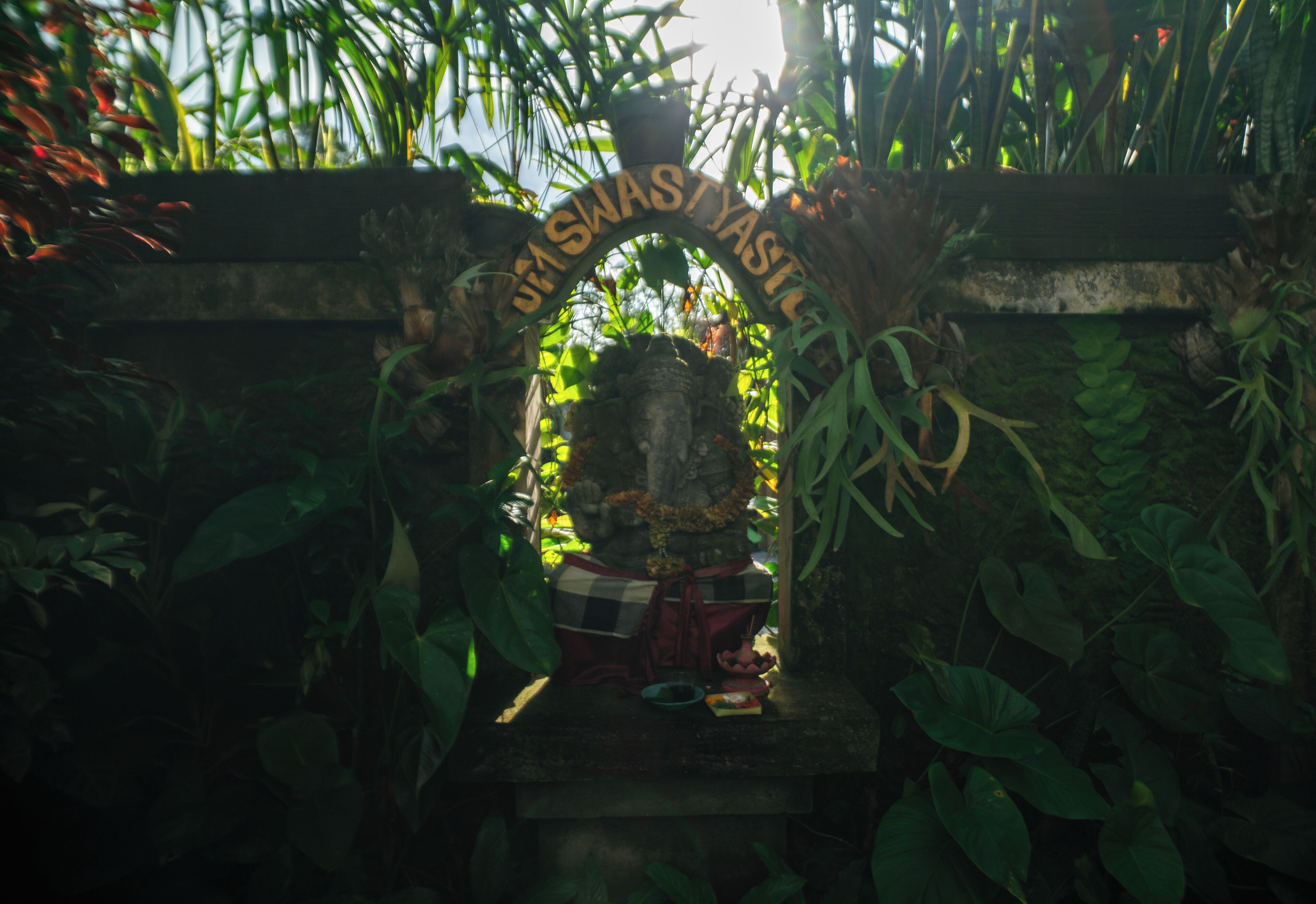 A shrine with a sign reading "JULIUS WASTYASTIL" surrounded by lush greenery.