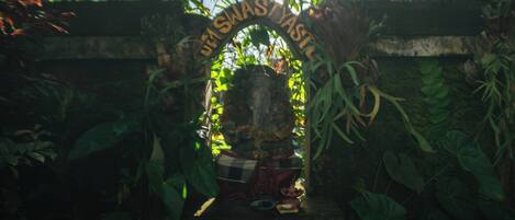 A shrine with a sign reading "JULIUS WASTYASTIL" surrounded by lush greenery.