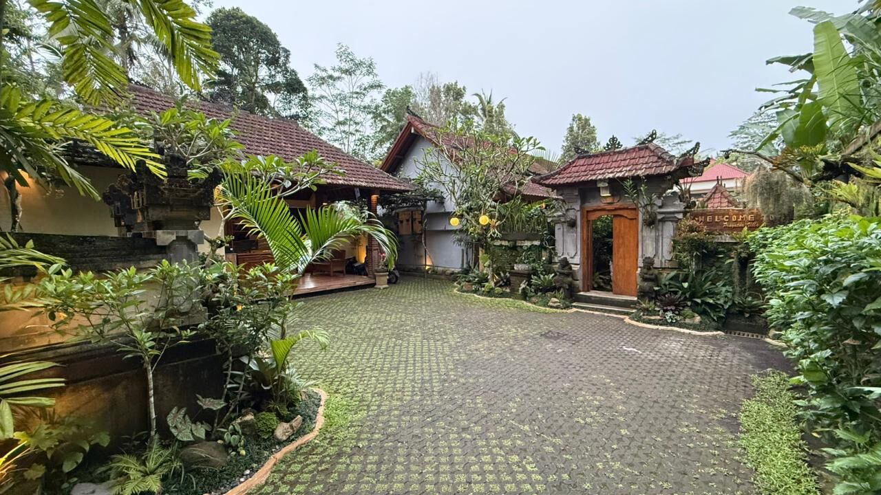 A courtyard with traditional architecture, a stone pathway, and lush greenery.