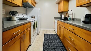 Una cocina con armarios de madera, un refrigerador blanco, una estufa y un lavamanos.