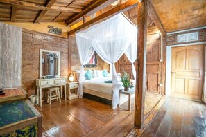 Una habitación rústica de madera con una cama bajo un dosel, un escritorio de madera y un espejo.