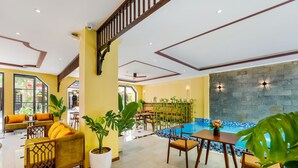Un vestíbulo de hotel con piscina, paredes amarillas y mobiliario de madera.