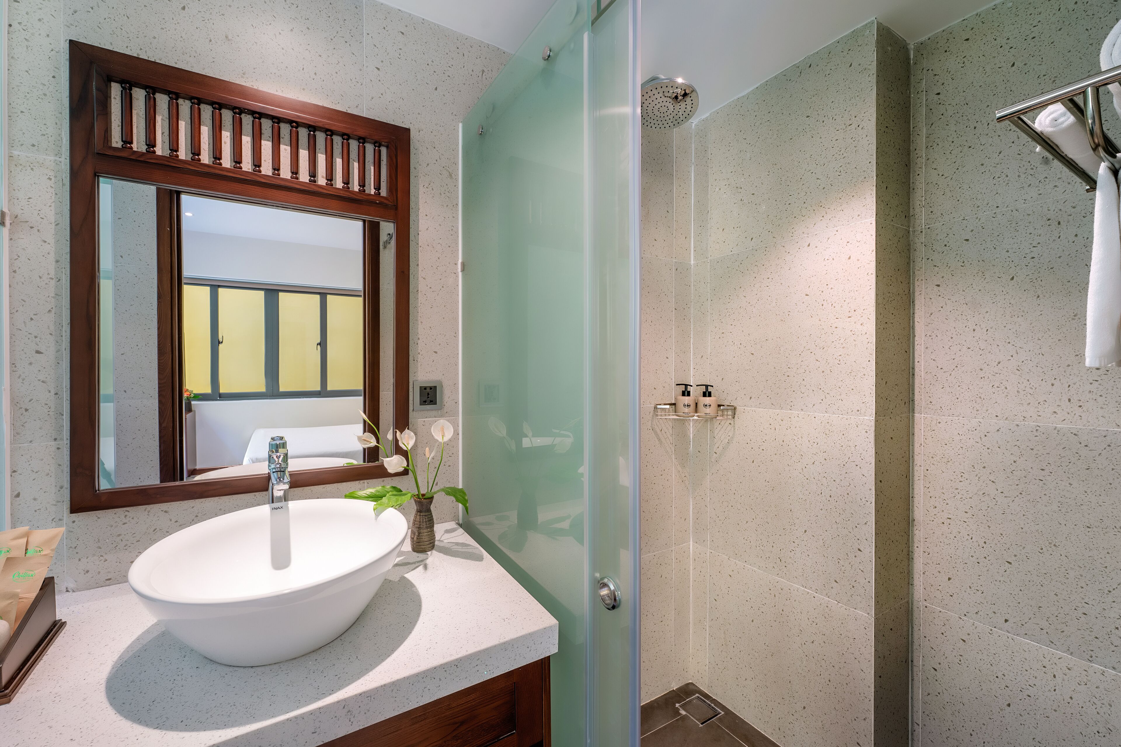 Un bagno con uno specchio grande, un lavandino bianco, box doccia in vetro e porta asciugamani.
