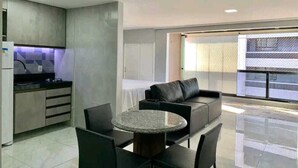 A modern kitchen with a dining area, a sofa, and a large window with a view. - Atlântico Vista Mar Deluxe (Fortaleza)