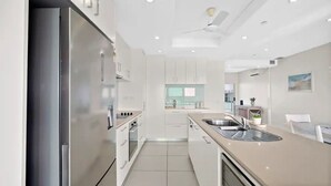 Una cocina moderna con armarios blancos, electrodomésticos de acero inoxidable y una isla grande con un lavamanos.
